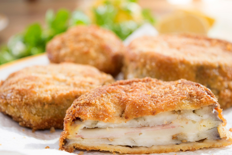 Melanzane in carrozza con doppia panatura dorate e filanti, servite su un piatto bianco.