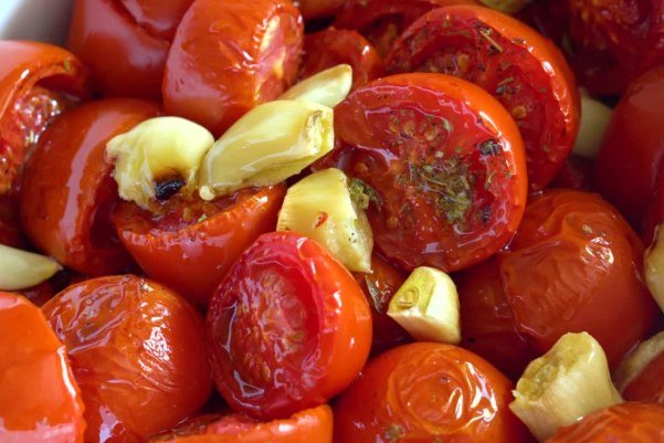 Pomodori al forno con 4 ingredienti, morbidi e dorati appena sfornati su teglia con carta forno